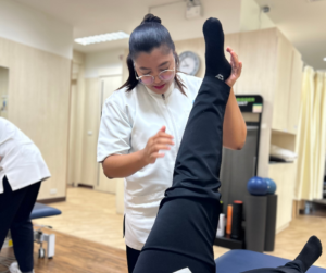 セラピストが仰向けになった人の左足をまっすぐ上に伸ばしている