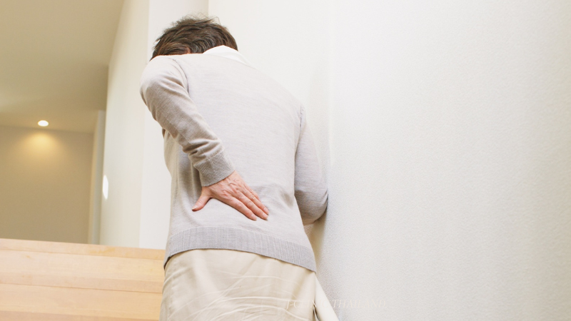 腰を抑えながら階段を上る中年の女性