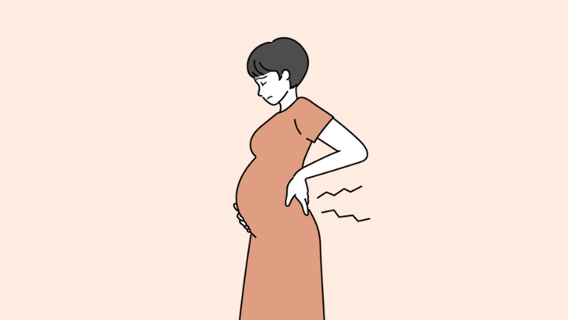 腰を痛そうに抑えているお腹の大きい妊婦