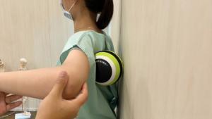 壁と背中の間にマッサージボールを挟んでいる患者様
