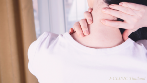 首を痛そうに手で押さえている後ろ姿の女性の写真