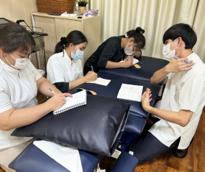 寝違えの際のテーピング治療について指導する先輩スタッフ