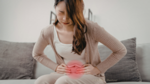 ソファに座ってお腹を痛そうに抑える女性