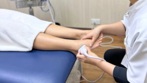 セラピストが患者様の足首にエコー検査機を当てている