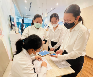 1人の女性が座っている、その人に対して話しかけている女性、それを見ている２人の女性