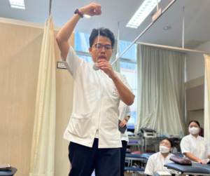 紐でつるしたおもりを顔の前でもって立っているセラピスト