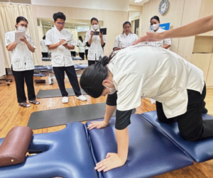 四つん這いになって背中を丸めているセラピストとそれを見ている、セラピスト5人