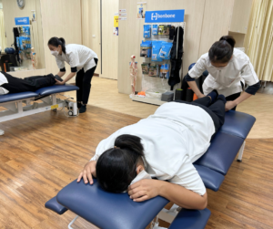 うつ伏せに寝ている人の足の長さを確認するセラピスト