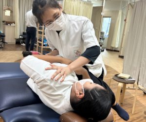 横を向いて寝ている人の方を持ち、もう１つの手で腰部を抑えている