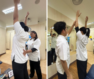 セラピストが両手をあかく上にあげている、そのセラピストの腰をもう一人のセラピストが触っている