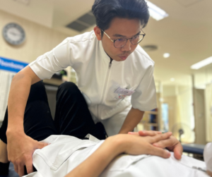 セラピストが仰向けになった人の腰を抑えている