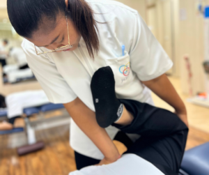セラピストがうつ伏せになった人の右膝を上に持ち上げている