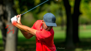 ゴルフのスイングをしている赤い服をきた男性